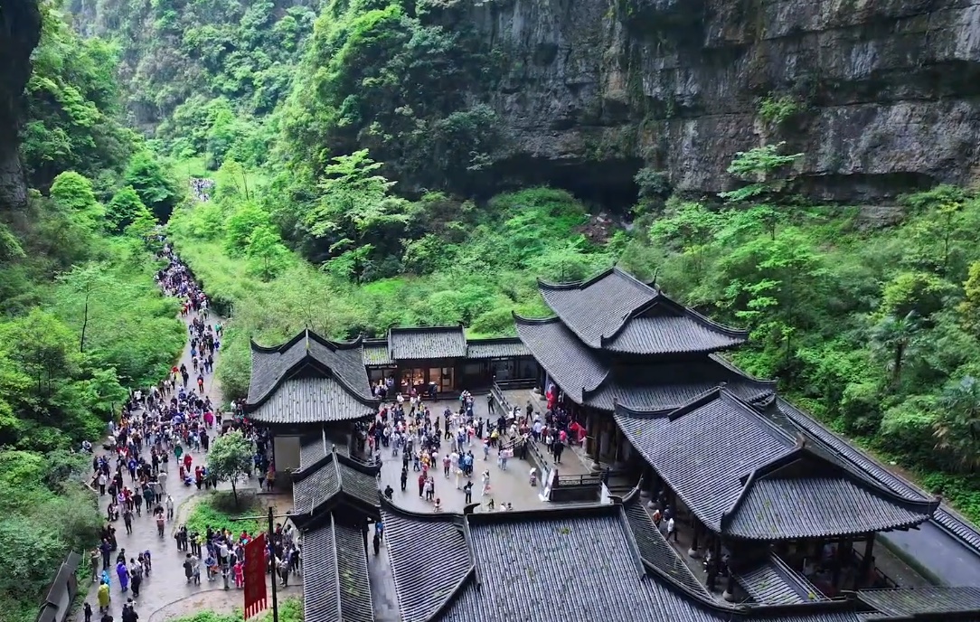 Traditional buildings below a natural rock arch in Wulong